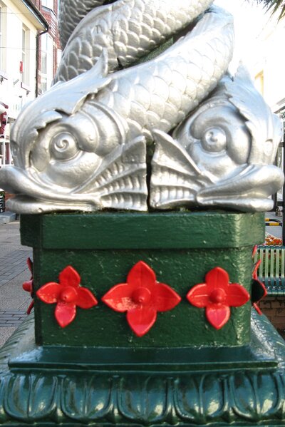 Two silver-painted large fish heads on ornamental lamp post