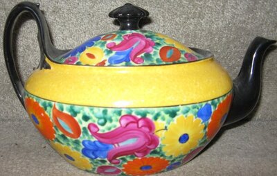 Floer pattern teapot with ellow band below li spout facing riht