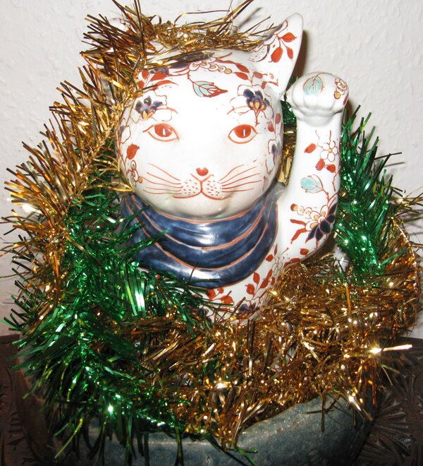 Ceramic Japanese calling cat with wreth of Christmas decoations in blue dish