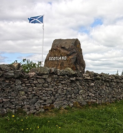 Scottish border with tone with Scotand in white letters, wall, andflagstaff with Scottish saltire on let