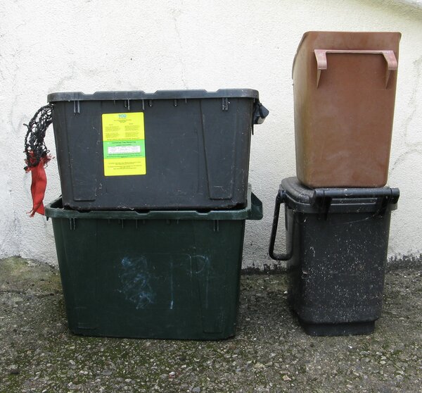 On left two black recycling boes one on top o another. On left brown food caddy on top of black one.
