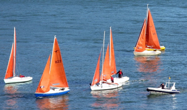 Red sailed dinghies on river