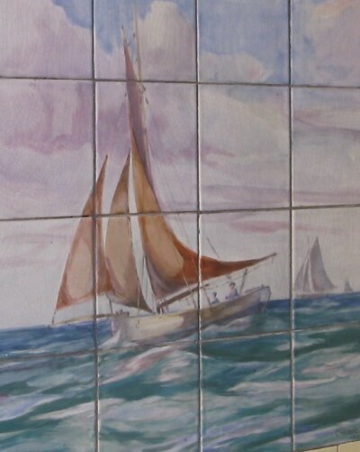 Tile design on wall of former butcher's Budleigh Salterton Devon Tile design of sailing boat heading left